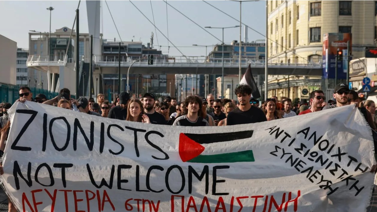 Pro-Palestinian demonstrators carry a banner during a protest against the arrival of an Israeli cruise ship in the port of Piraeus near Athens, Greece, June 12, 2025. (photo credit: REUTERS/Louisa Gouliamaki)